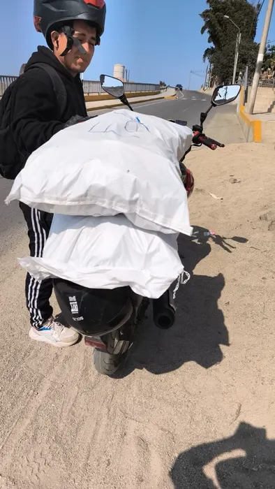 Repartidor con sacos de separadores de concreto en una motocicleta